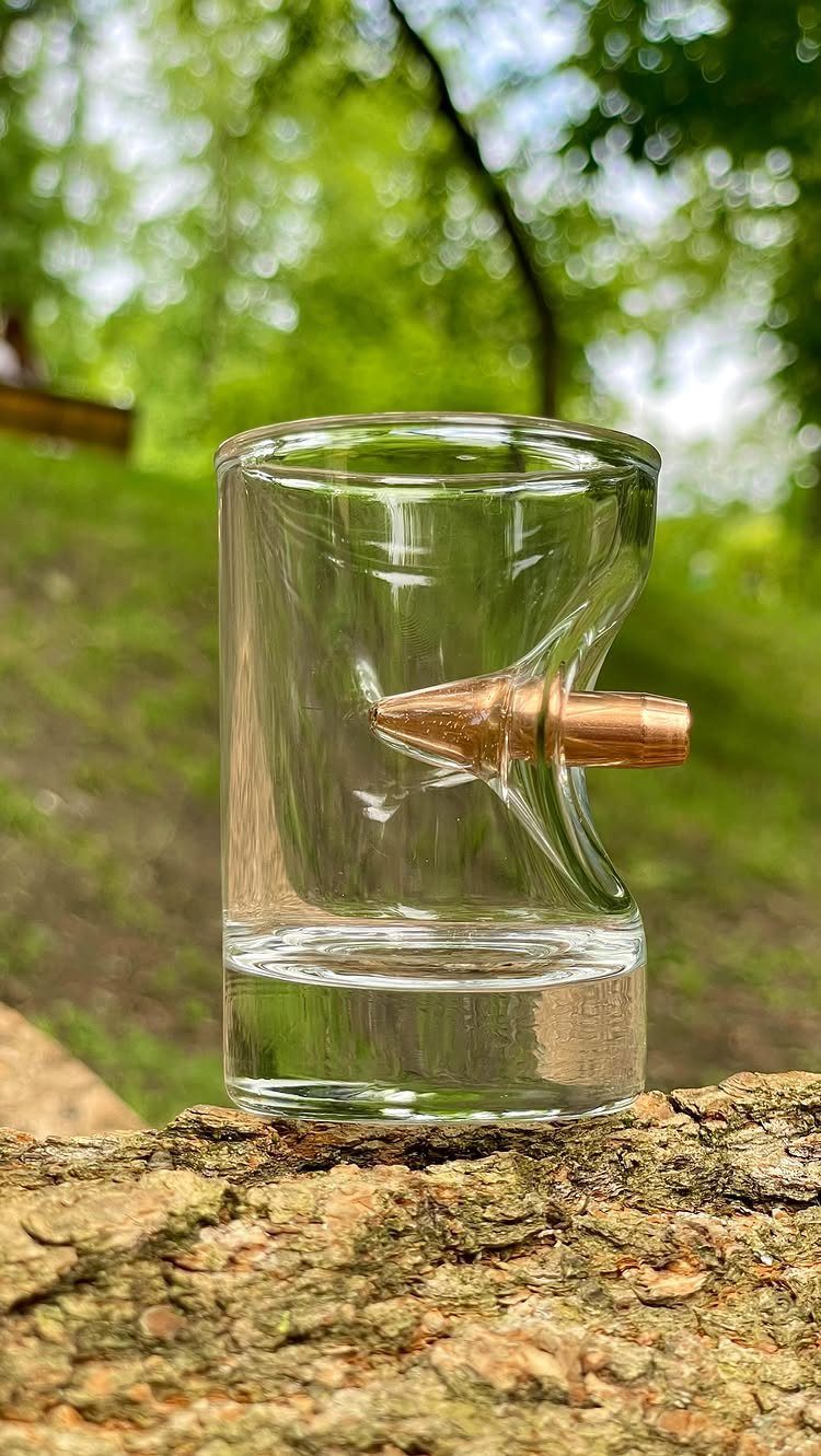 Bullet rock glass with a copper bullet embedded in the side on bark