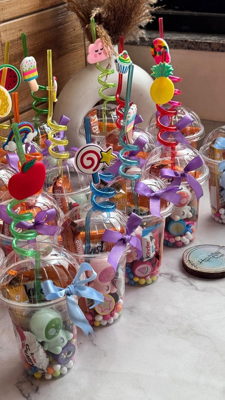 Clear plastic cups filled with candies and toys, topped with colorful curly straws.