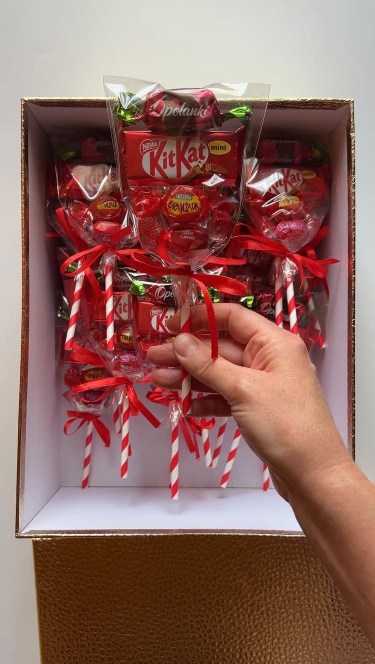 Candy bouquets with KitKat bars and red ribbons in a gold box.