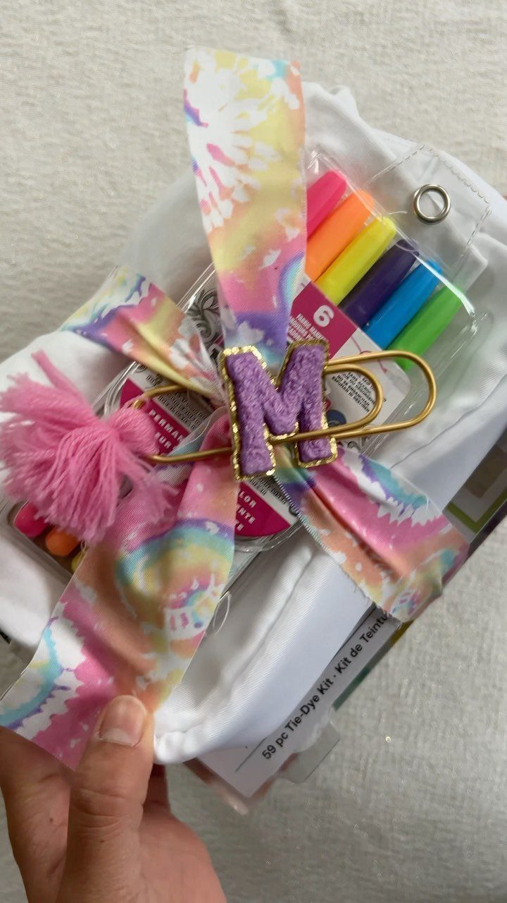 Tie-dye kit in a white pouch decorated with a colorful ribbon and glittery letter.