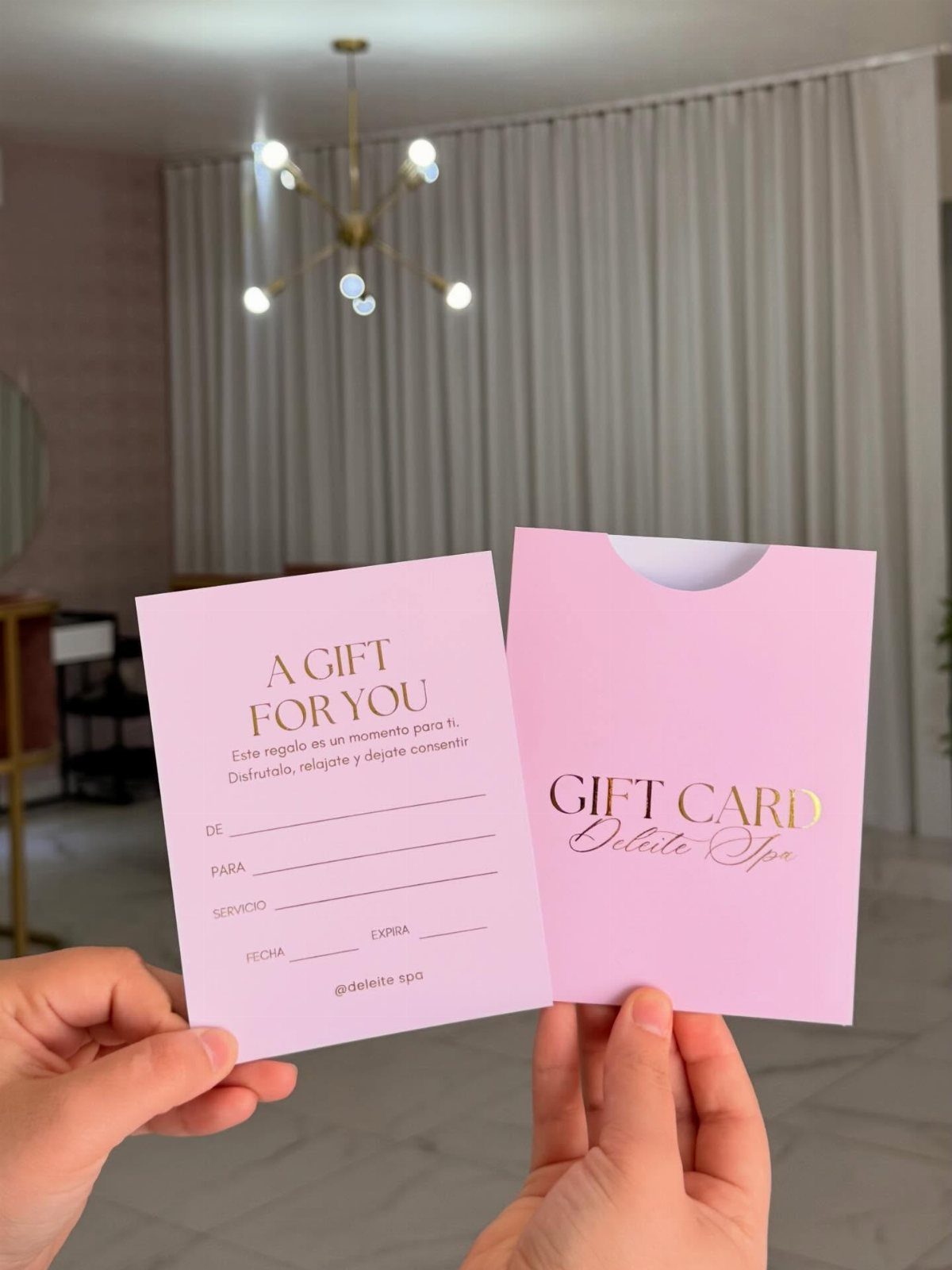 Pink spa gift card and envelope held by hands in a bright room.