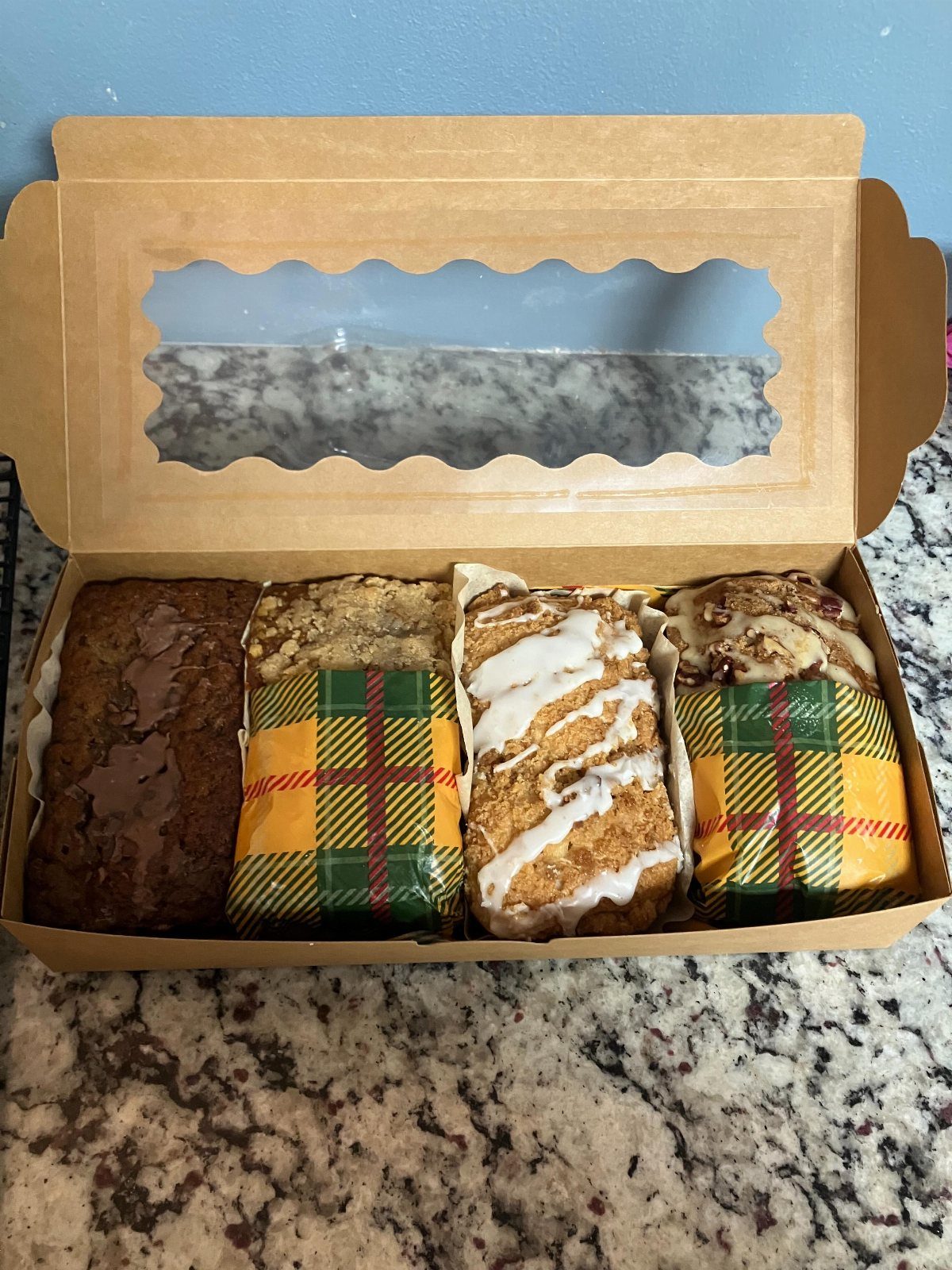 Assorted sliced quick breads in a cardboard gift box with plaid wrapping.