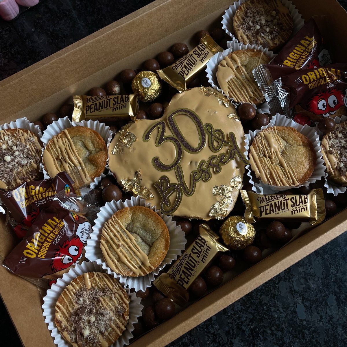 Assorted sweets and a heart-shaped cookie in a cardboard gift box.