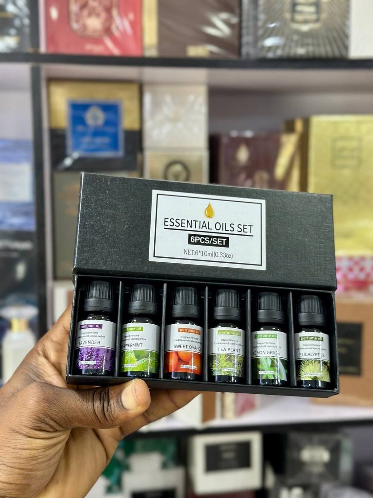 Essential oils set in a black gift box held by a hand.
