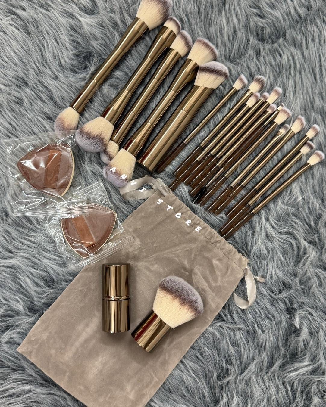 Makeup brushes and beauty sponges arranged on a grey faux fur background.