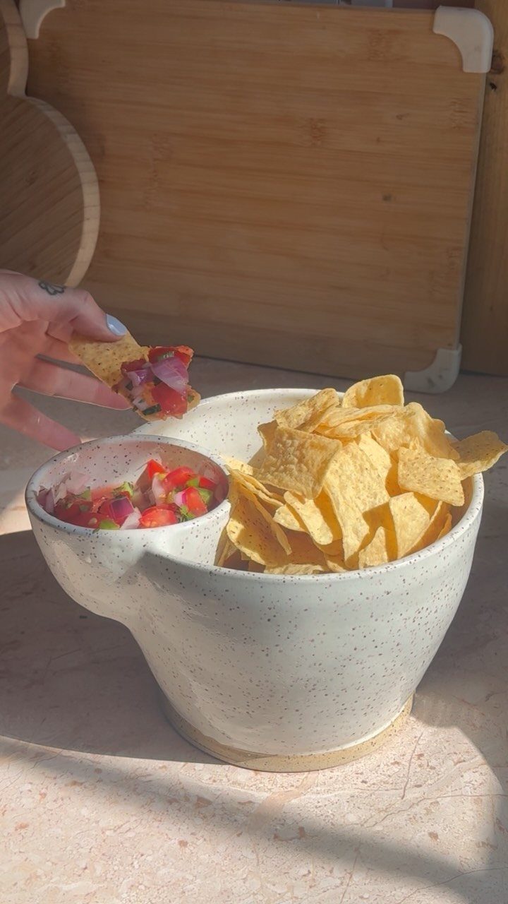White ceramic chip and dip bowl filled with tortilla chips and fresh salsa.