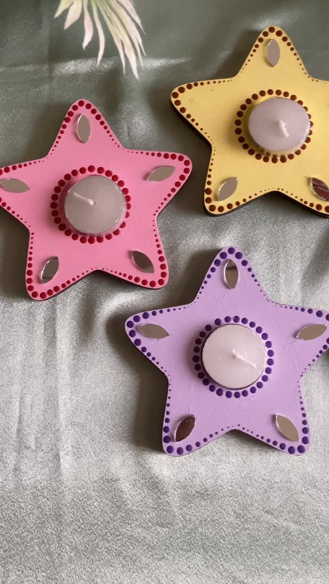Three colorful star-shaped tea light holders with small white candles and mirror accents.