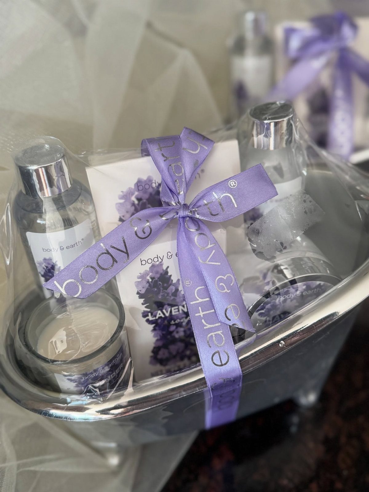Lavender bath gift set in a silver basket tied with a purple ribbon.