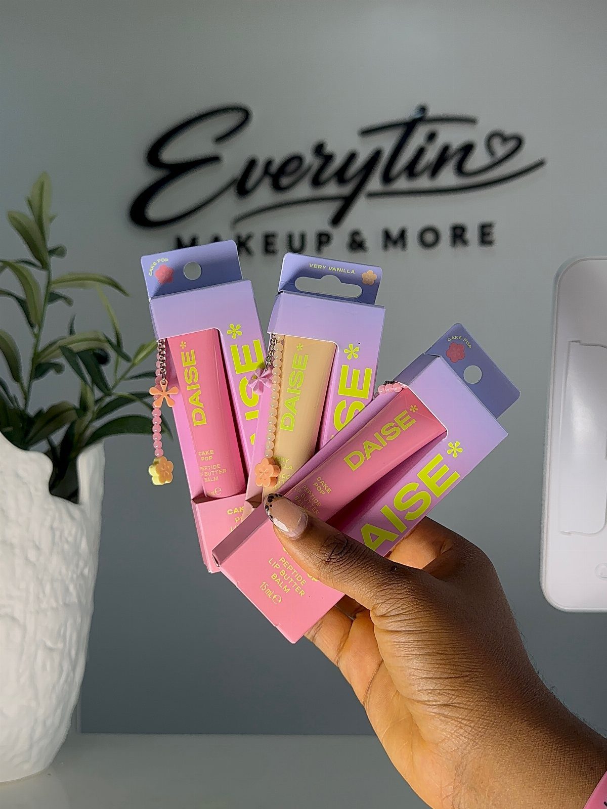 Lip butter tubes in pink and purple packaging held by a hand.