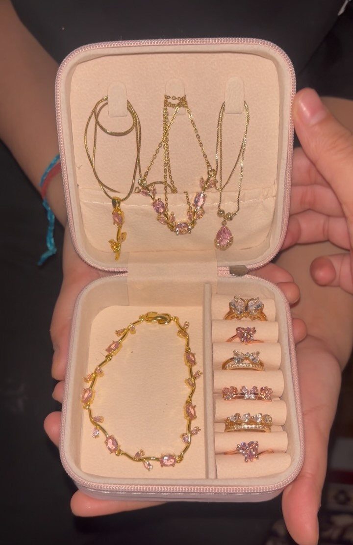 Gold jewelry set with pink gemstones in a small pink travel organizer case.