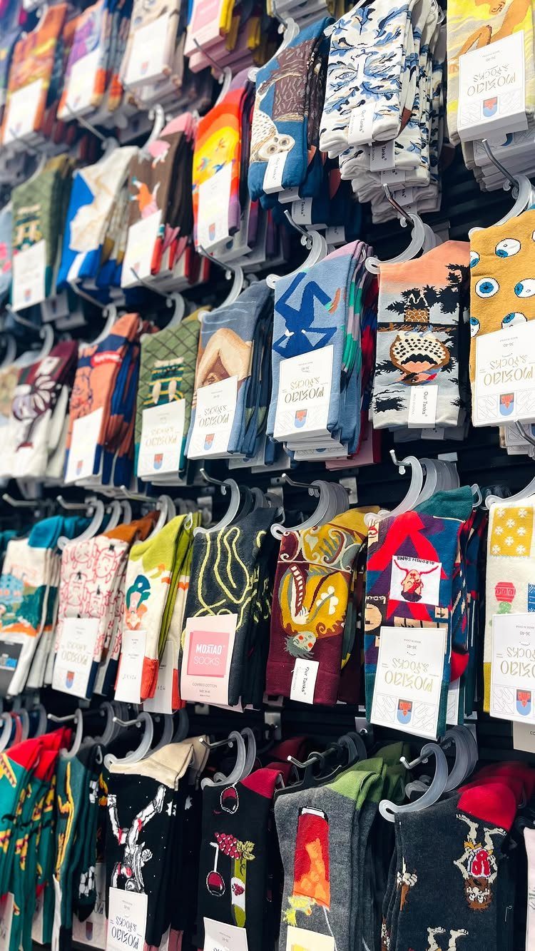 Colorful patterned socks hanging on a retail display rack with white price tags.