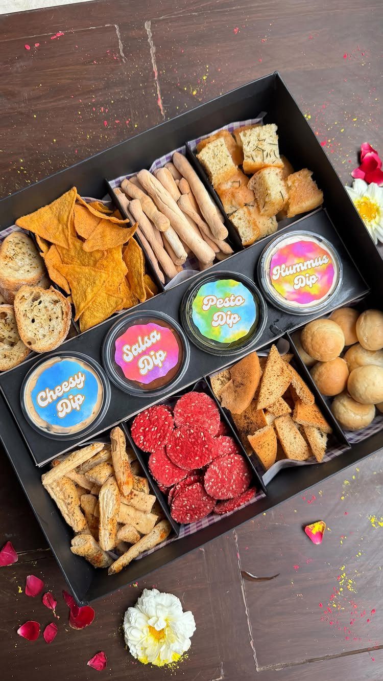 Gourmet food basket with assorted snacks and dips in a black box.