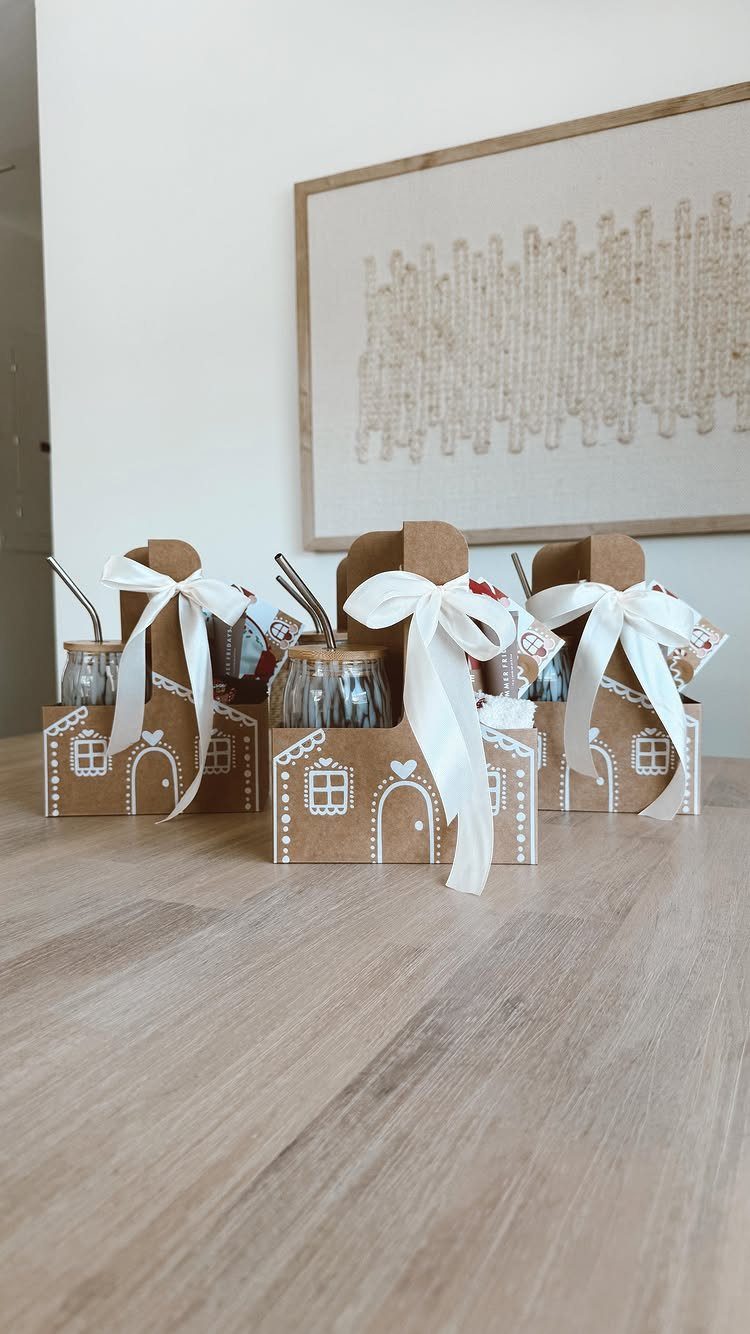 Three house-shaped cardboard gift boxes containing small glass jars with spoons and ribbons.