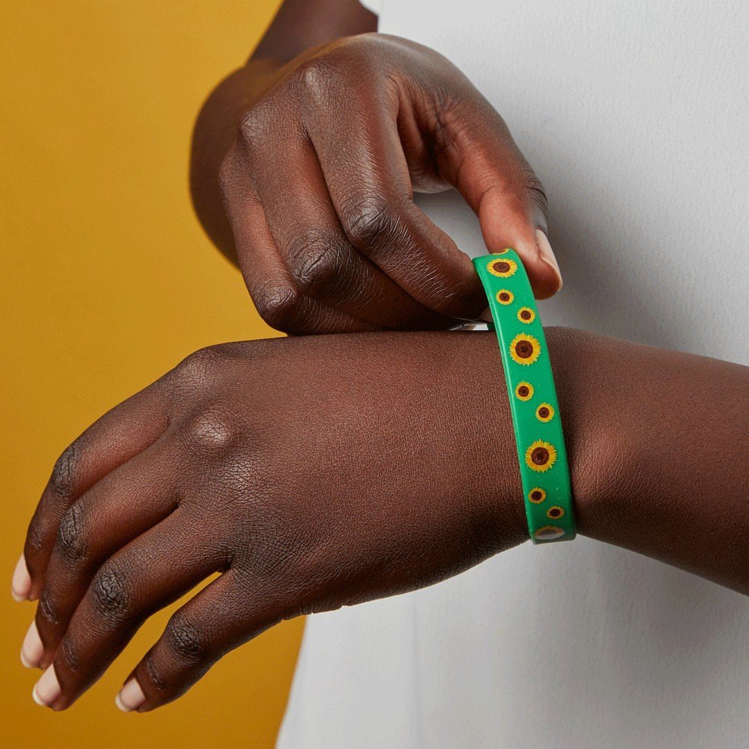 Green acrylic bangle bracelet with yellow sunflowers worn on a person's wrist.