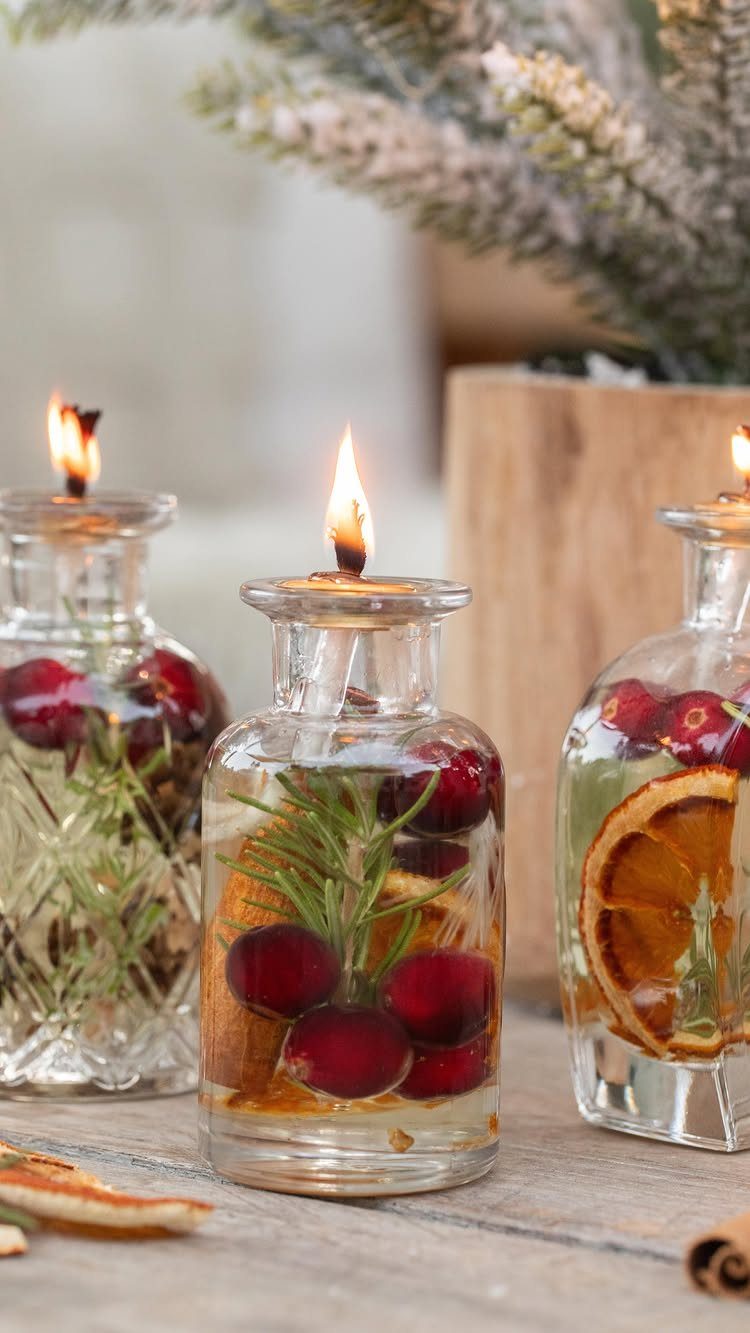 Glass oil bottles with cranberries and rosemary used as lit decorative candles.