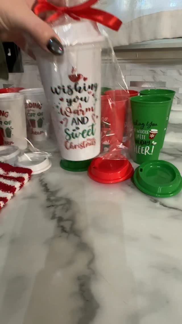 Festive Christmas tumblers wrapped in cellophane with red ribbons on a marble counter