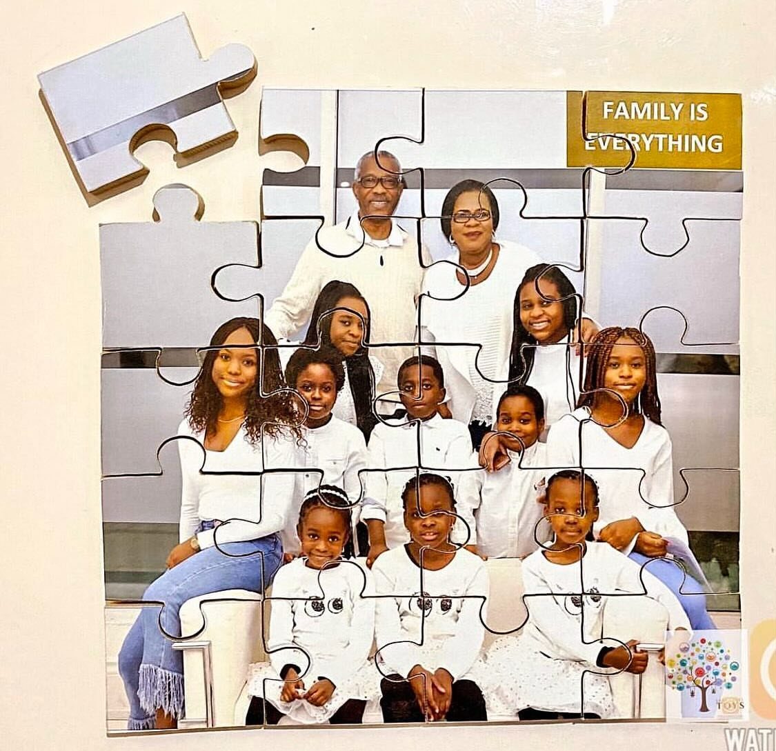 Family portrait printed on a large assembled jigsaw puzzle mounted on a wall.
