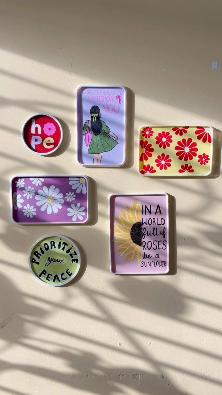 Colorful ceramic trays with floral patterns and motivational quotes on a light surface.