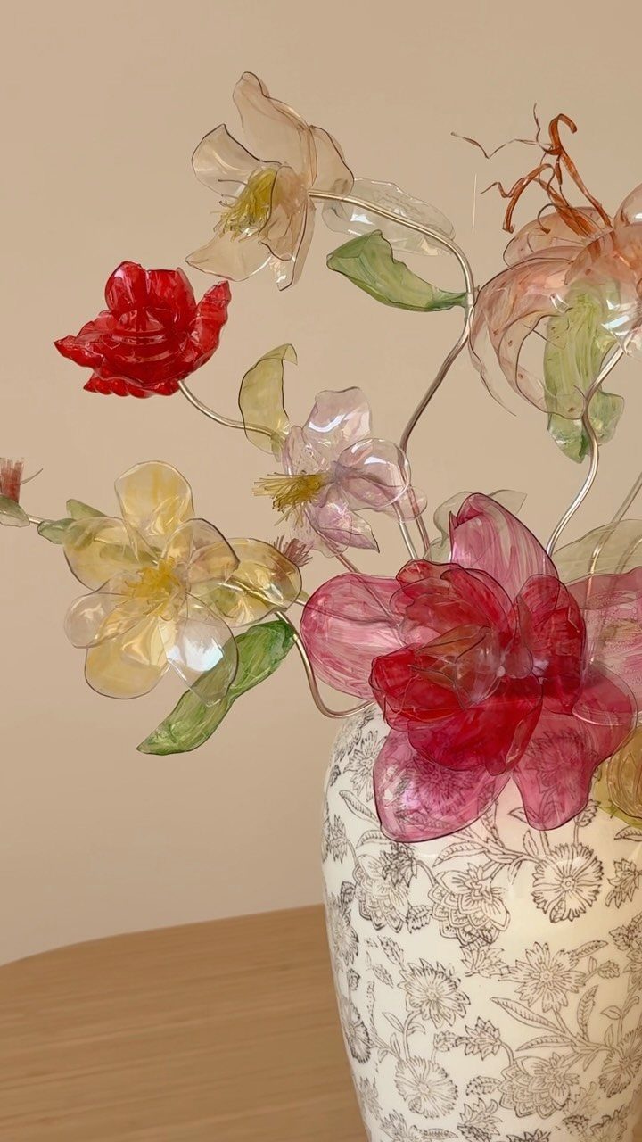 Glass flowers in red, yellow, and pink colors inside a floral patterned vase.