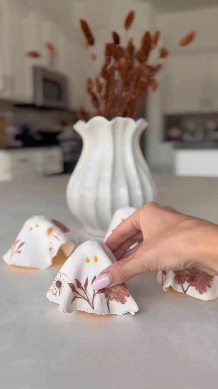 Hand-painted ghost ceramic figures with floral designs on a grey kitchen counter.