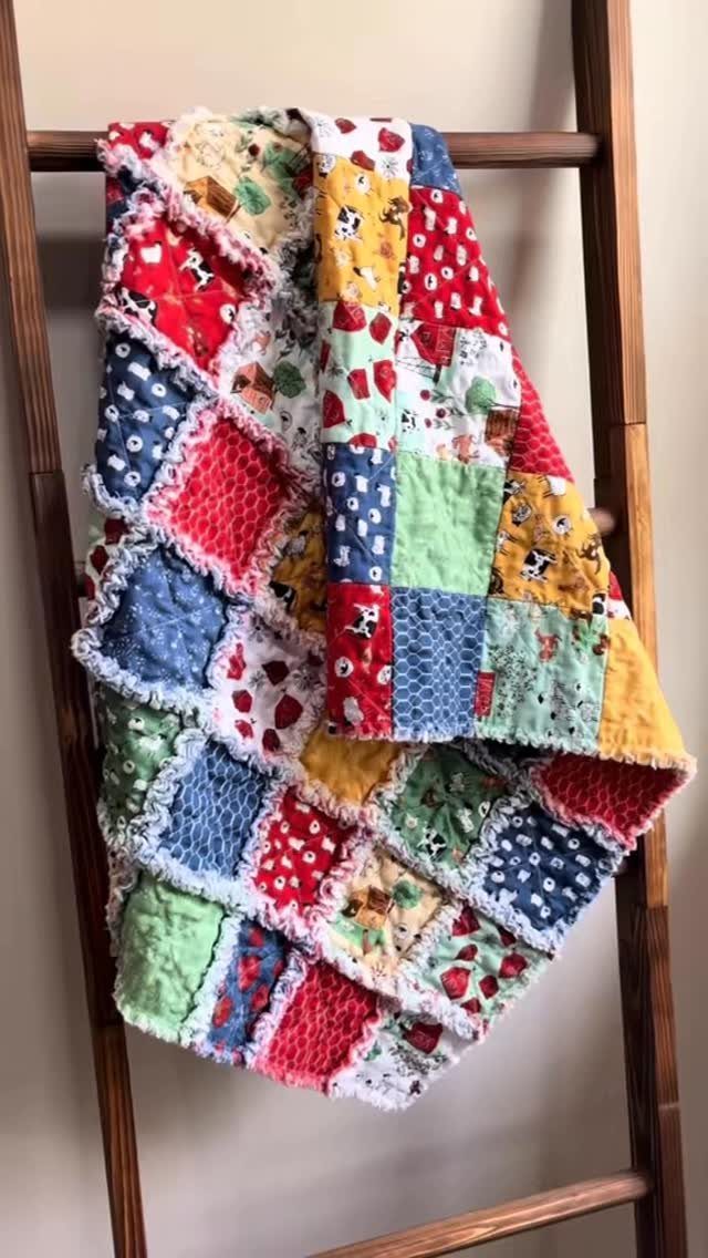 Colorful scrap fabric rag quilt draped over a wooden ladder against a wall.