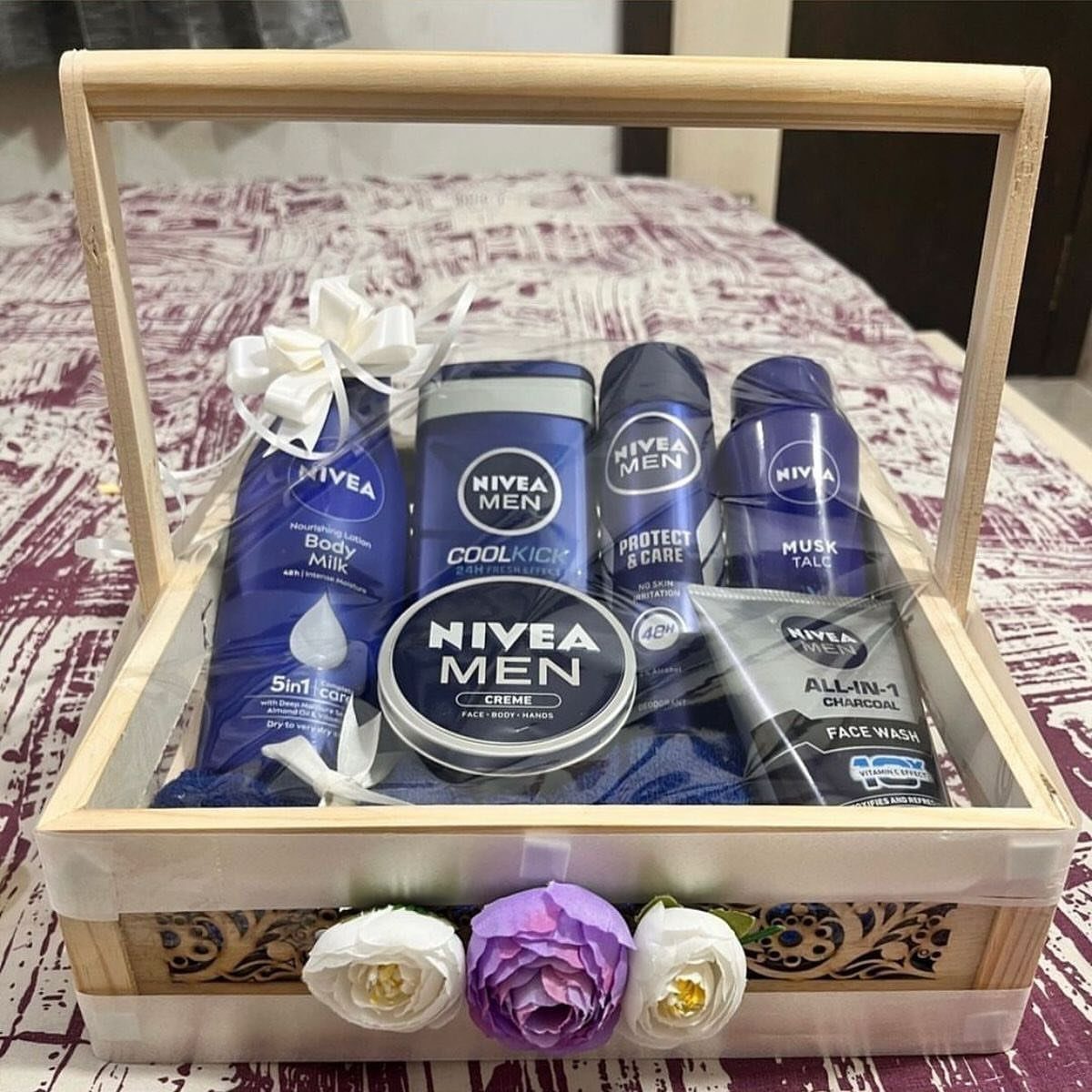 Nivea Men grooming products arranged in a wooden gift basket with artificial flowers.