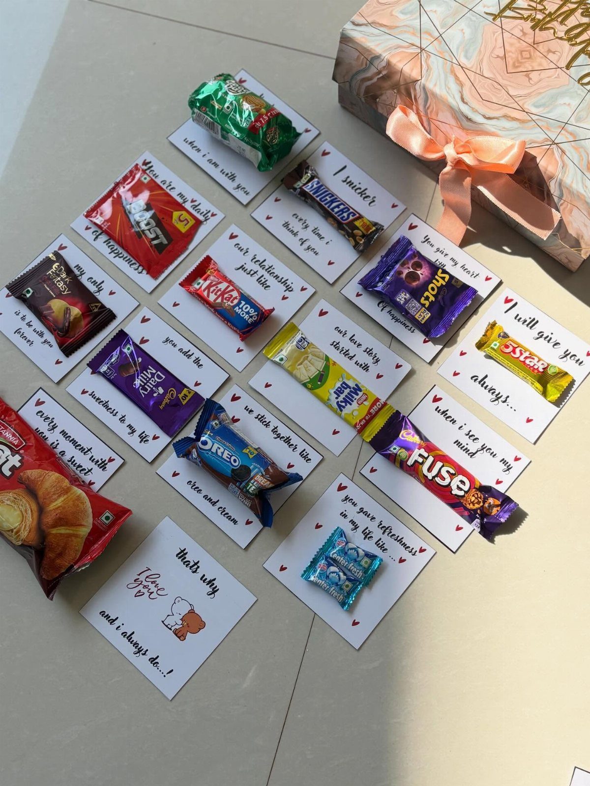 Assorted chocolates and candies on handwritten note cards next to a wrapped gift.