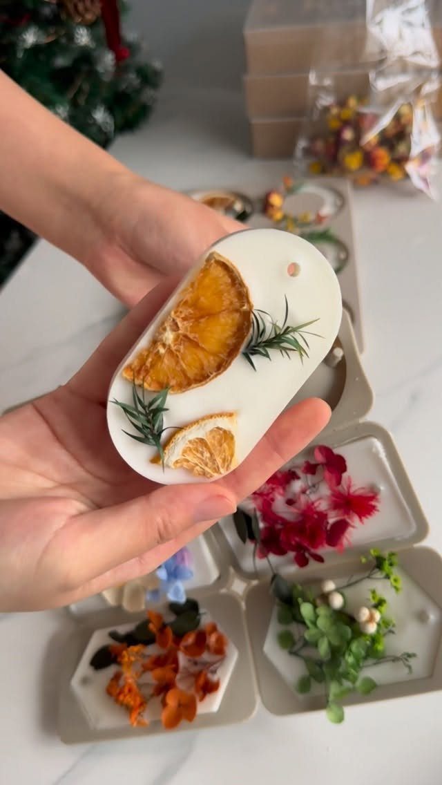 White wax sachet with dried orange and rosemary held in two hands.