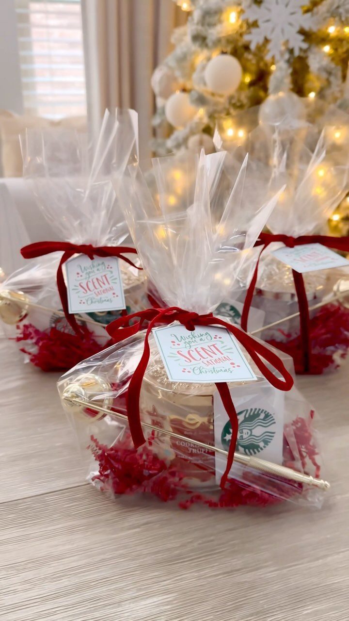 Three cellophane gift bags with red ribbons, candles, and Starbucks gift cards.