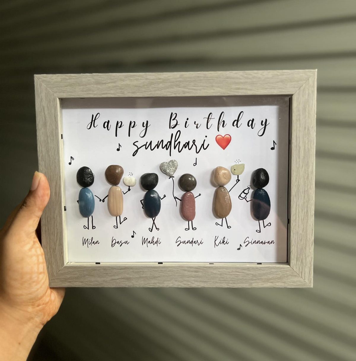 Pebble art figures in a grey wooden frame for a birthday gift.