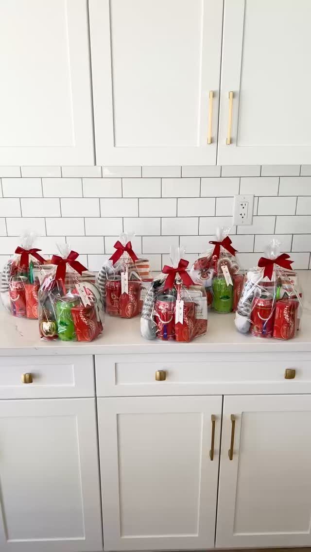 Six clear gift bags with red ribbons filled with colorful candies on a counter