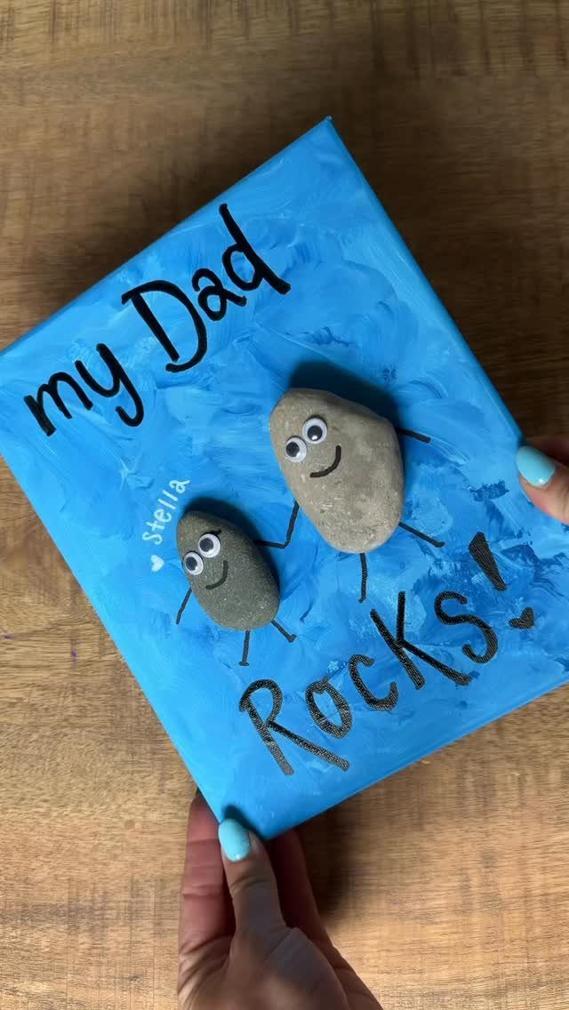 Blue canvas with two googly-eyed rocks and text saying my Dad Rocks!