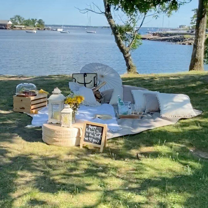 Picnic setup with pillows and lanterns on a blanket by a calm lake