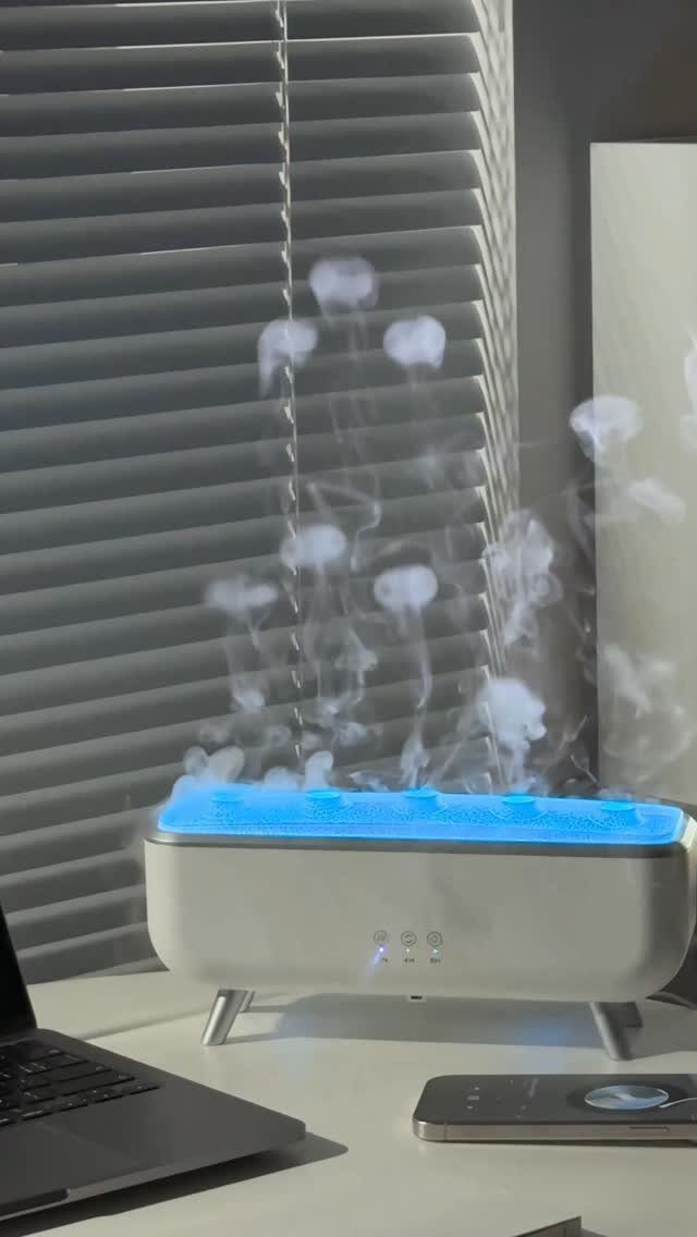 White humidifier emitting bubble-like mist on a desk next to a laptop and phone