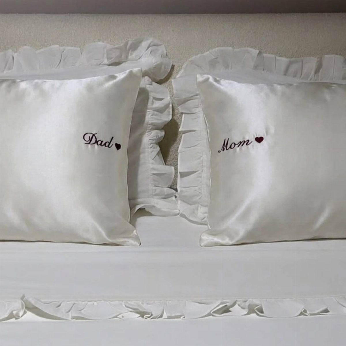 Two white satin pillowcases embroidered with Dad and Mom and red hearts.