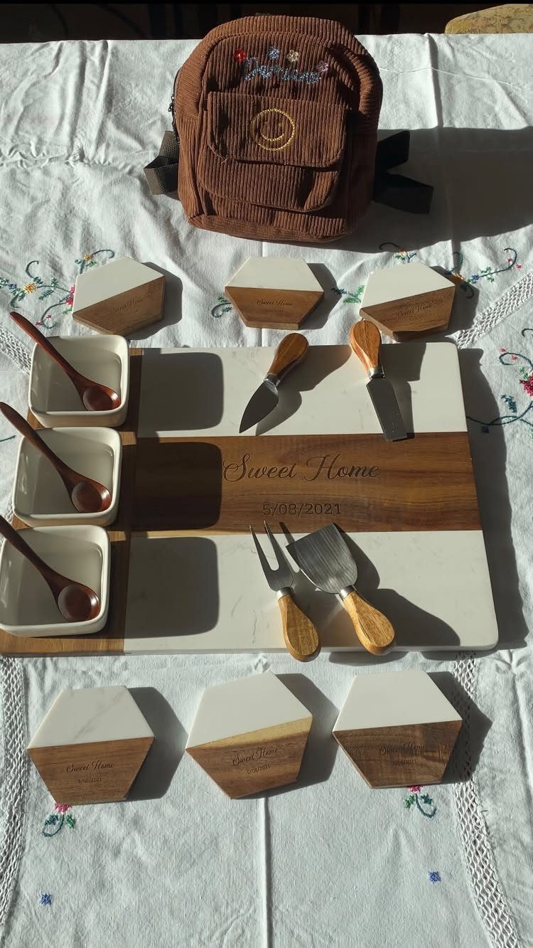 Engraved marble and wood charcuterie board with cheese knives and small serving bowls