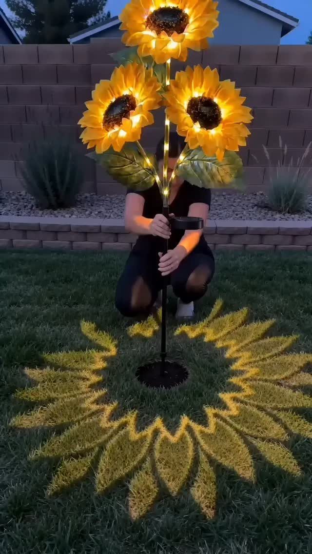Solar sunflower garden light projecting a glowing yellow flower pattern onto green grass.