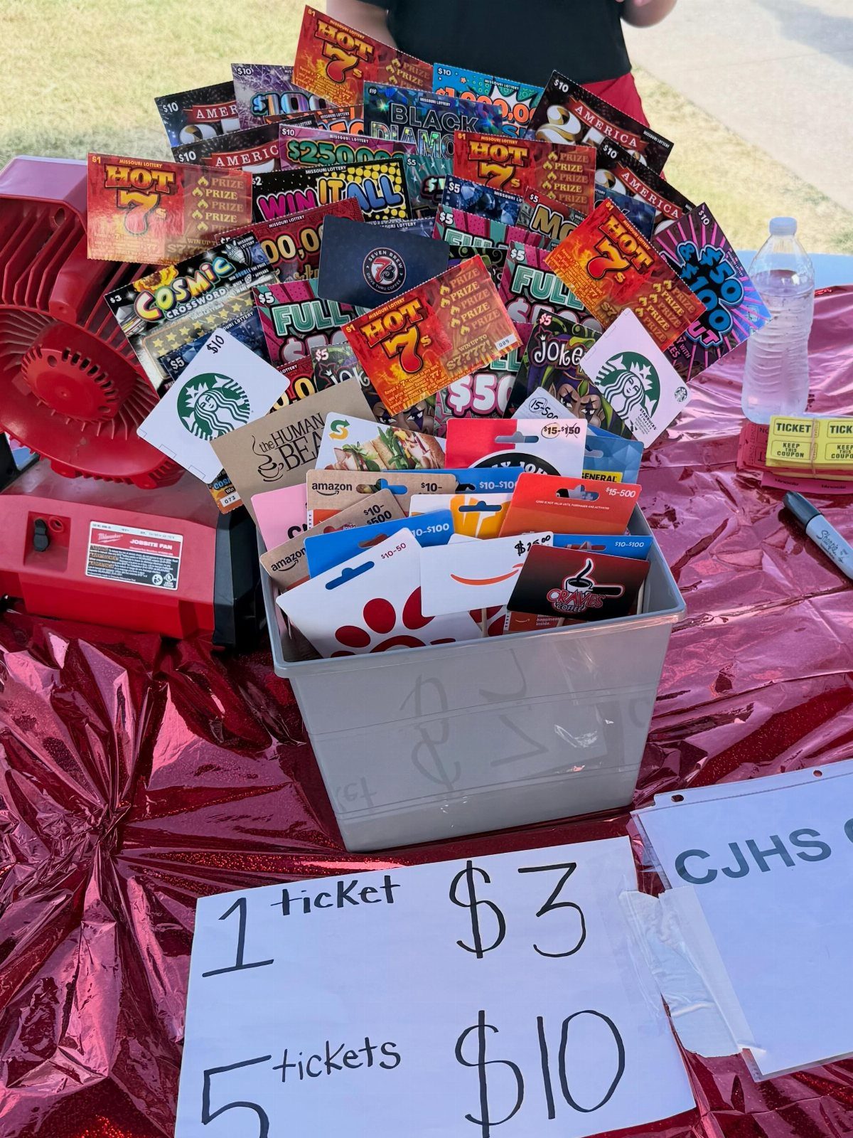 Gift cards and vouchers in a bin on a red metallic table.
