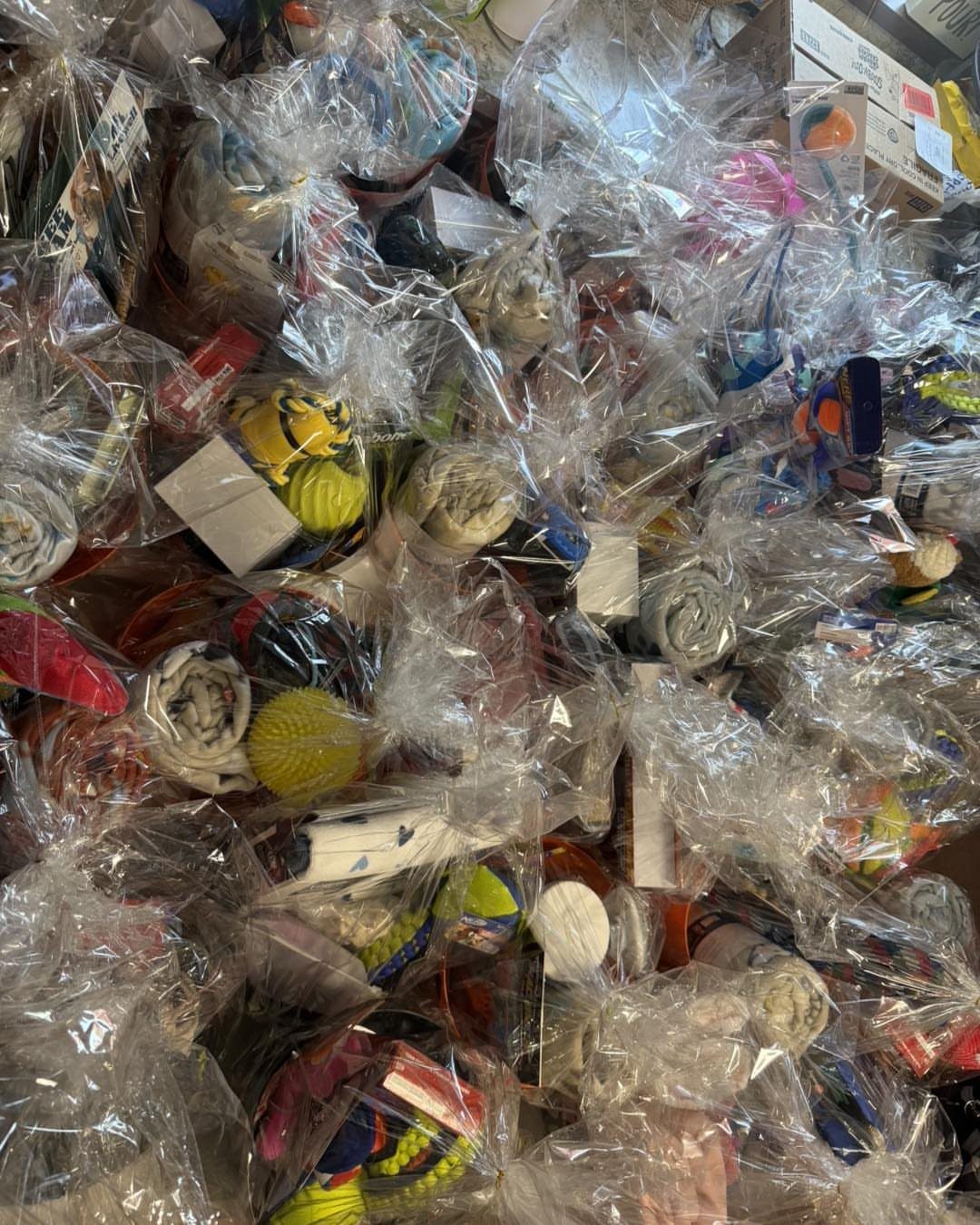 Small colorful gift items wrapped in clear cellophane bags piled together.