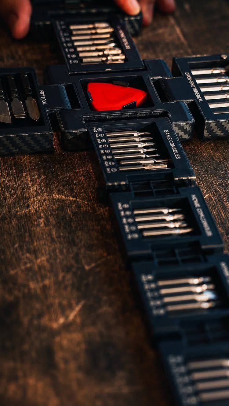 Precision screwdriver set with metal bits in a black modular case on wood.