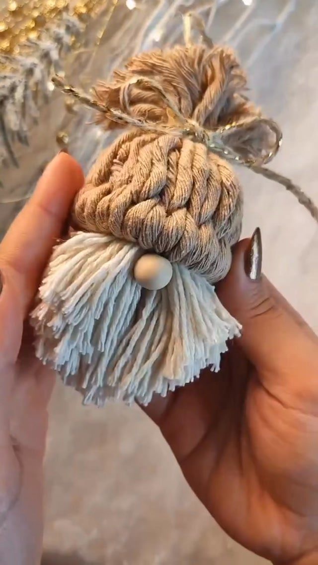 Handmade gnome ornament made of beige and white twine held in two hands.