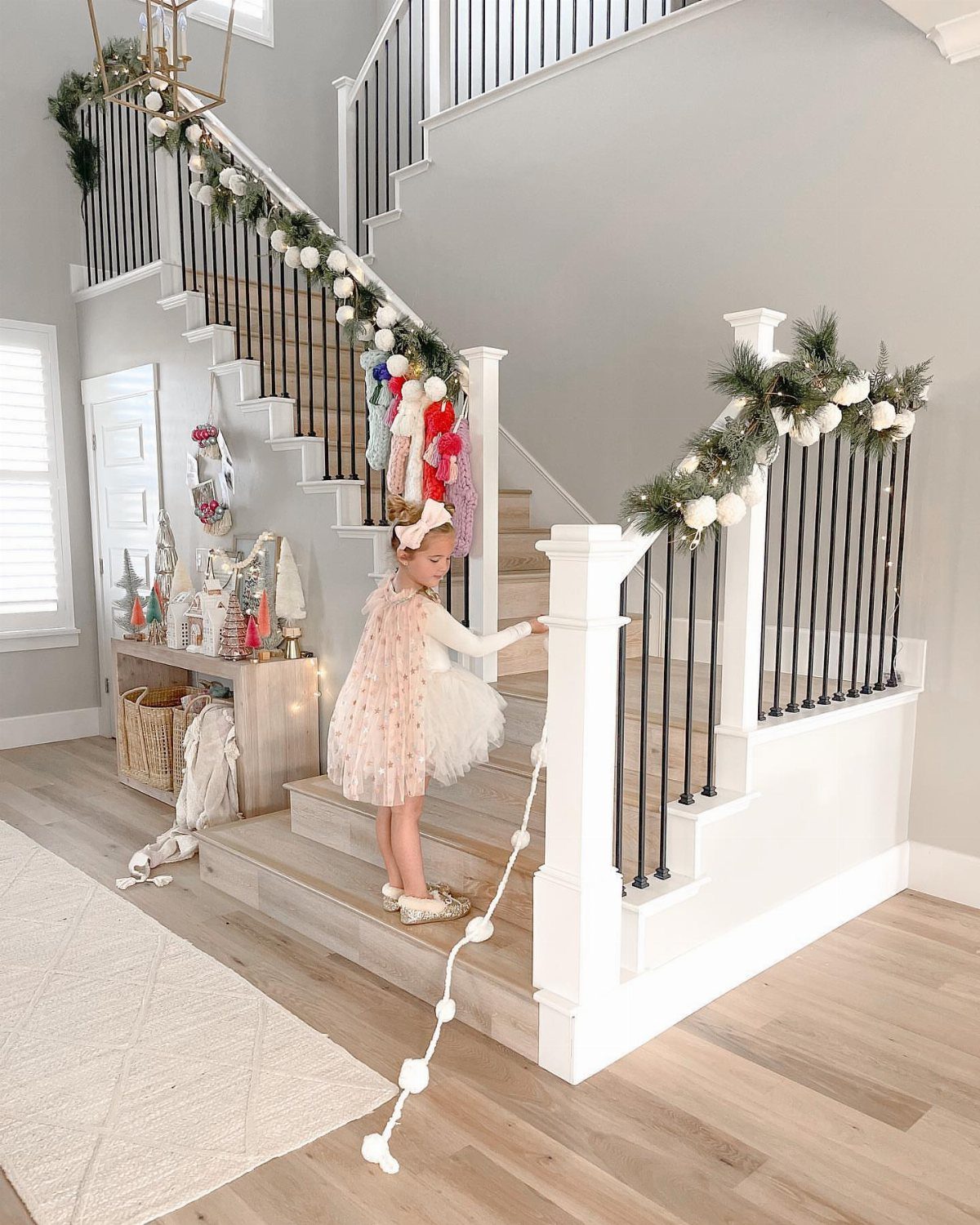 Young girl in pink tutu holding a white pom pom garland on stairs