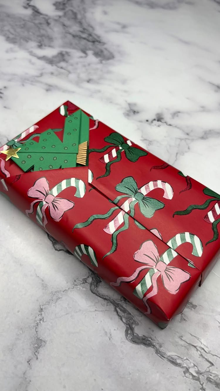 Wrapped red Christmas gift box with candy cane patterns and a paper tree decoration.