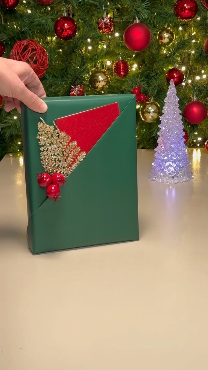 Green wrapped gift box designed as an elf in front of Christmas trees