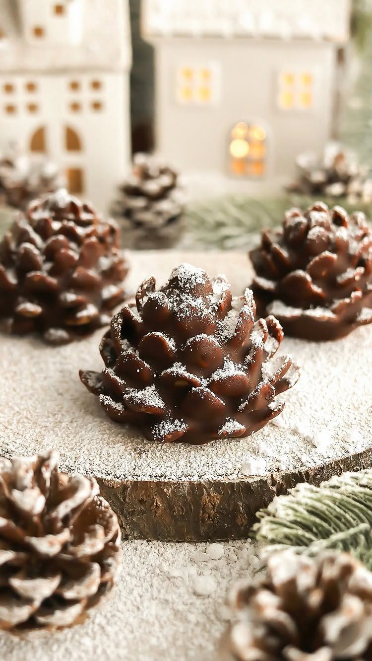 Chocolate pine cone treats with powdered sugar on a rustic wooden slice