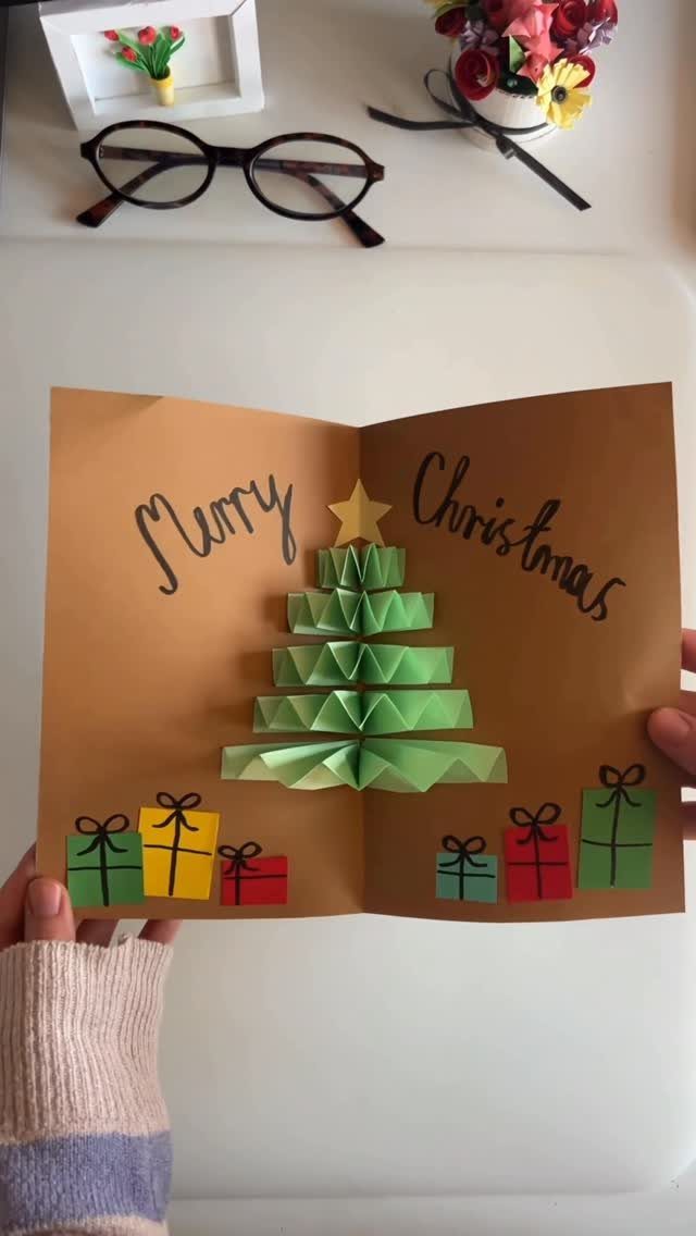 Handmade Christmas card with a 3D green paper tree and colorful gift boxes.
