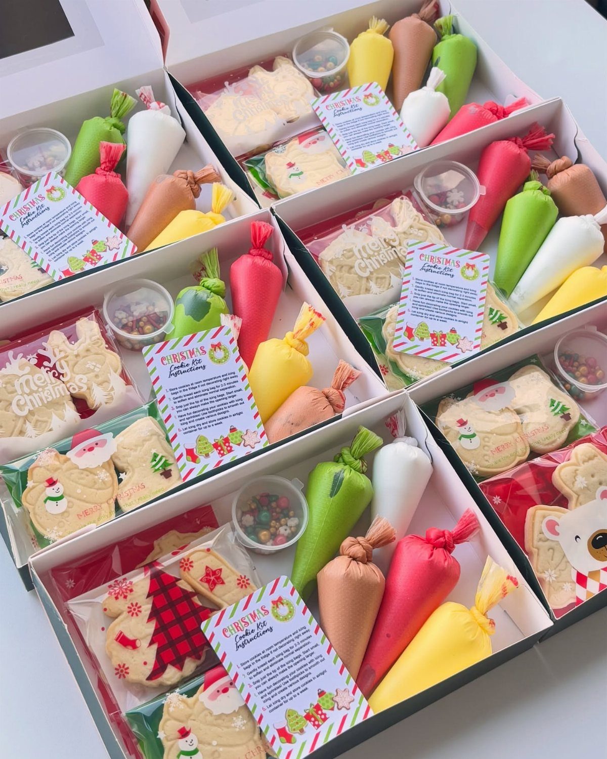 Christmas cookie decorating kits with cookies, frosting piping bags, and sprinkles in boxes