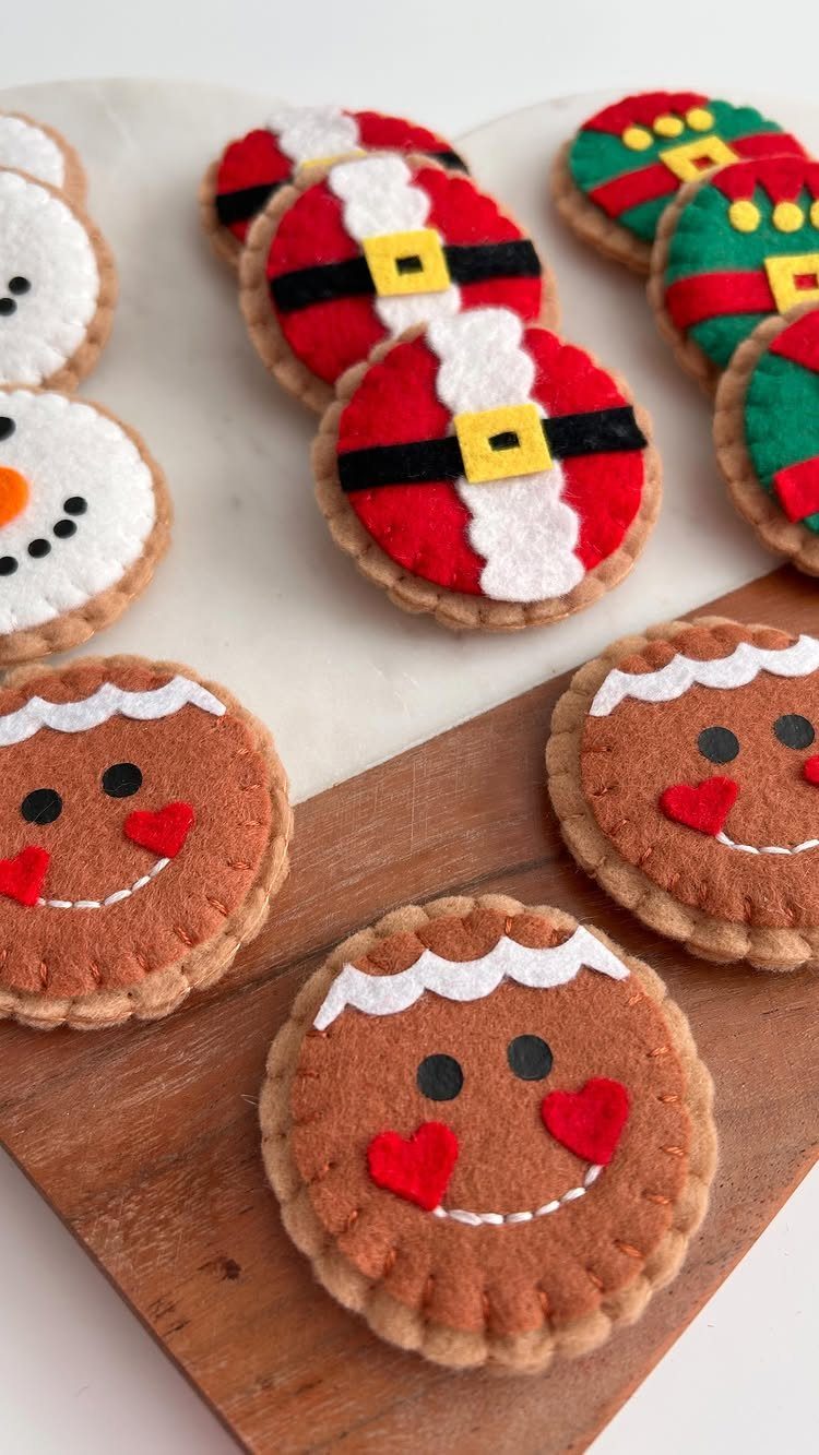 Felt craft cookies shaped like gingerbread men, snowmen, and Santa Claus on wood.