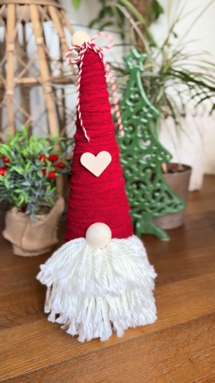 Handmade gnome with red yarn hat and white beard on wooden table