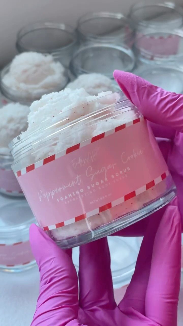 Hand in pink glove holding a jar of white peppermint sugar scrub.
